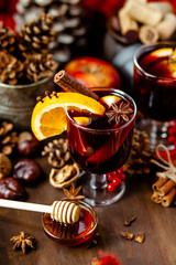 Two glasses of hot red mulled wine decorated with orange, clove, cinnamon and anise. Christmas lights on background. Rustic decor, cozy atmosphere, festive mood. Family time, new year eve
