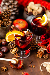 Two glasses of hot red mulled wine decorated with orange, clove, cinnamon, anise. Christmas lights on background. Rustic decor, cozy atmosphere, festive mood. Family time, new year eve, festive mood
