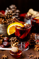 Two glasses of hot red mulled wine decorated with orange, clove, cinnamon, anise. Christmas lights...