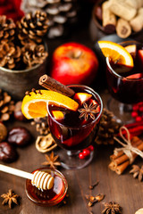 Two glasses of hot red mulled wine decorated with orange, clove, cinnamon and anise. Christmas lights on background. Rustic decor, cozy atmosphere, festive mood. Family time, new year eve