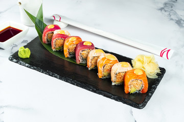 Set sushi rolls served on a banana leaf on a black stone on a marble table with chopsticks and soy sauce. Japanese food. Salmon and Tuna Shrimp Sushi. Healthy seafood. Food photo