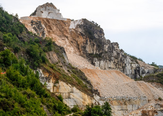Fototapeta na wymiar Marble extraction at the famous Carrara white marble quarries. Image clearly shows how much mountain has been removed. Apuan Alps, Italy.