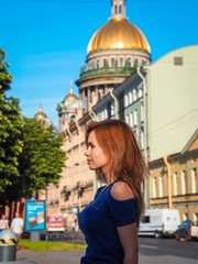 Brunette girl with long hair enjoys the evening sun on the background of St. Isaac's Cathedral in St. Petersburg