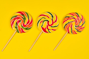 Colorful candy on a yellow  background. Lollipop. Top view. Copy space.
