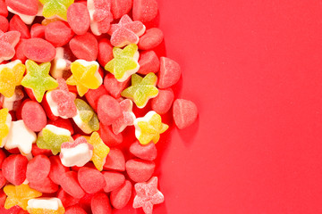 Assorted colorful gummy candies and lollipop on red background. Top view. Jelly  sweets.