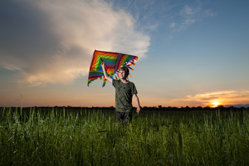 A child plays with a kite at sunset in the field.