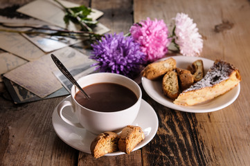 Cup of hot chocolate, cookies and flowers on an old wooden table