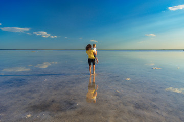 Mother and baby are looking over the horizon. Mom with a baby in her arms are among the water and...