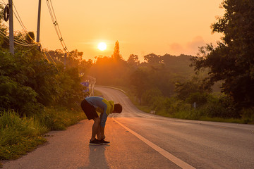 Runners tied to running shoes on the road in the morning with sunrise to exercise for a healthy and...
