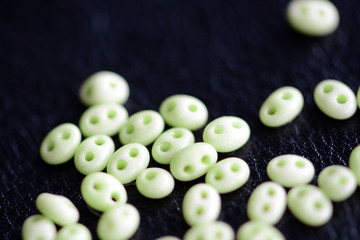 Twin beads light green color scattered on a dark surface close up