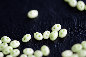 Twin beads light green color scattered on a dark surface close up