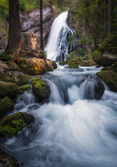 Scenic waterfall landscape with green moos stones and flowing river at beautiful summer day in Gollinger, Austria.