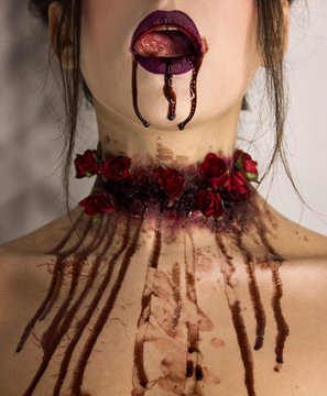 tasty blood flows from the open mouth with tongue and neck with red roses. halloween concept, close-up