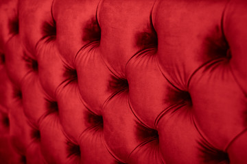 Red luxury velour quilted sofa upholstery with buttons, elegant home decor texture and background