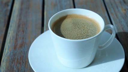side view on ceramic white cup of coffee on wooden table