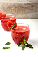 Watermelon smoothie fresh juice with mint and pieces in the shape of hearts on a white background. Summer healthy drinks.