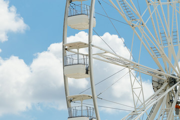 Ferris wheel on the blue cloudy sky. Background concept of happy holidays time.