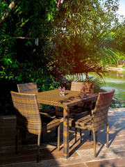 Rattan dining table furniture set on wooden terrace near the river view.