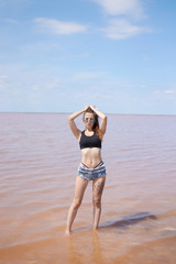 Young sexy fit curvy woman posing near the pink lake