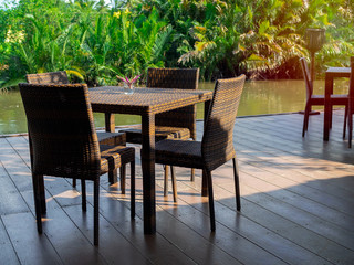 Obraz premium Rattan dining table furniture set on wooden terrace.