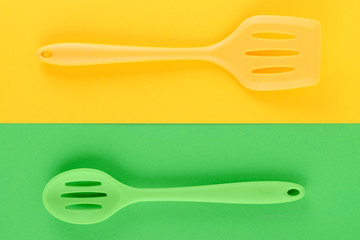 bright kitchen utensils on yellow and green background, creative idea