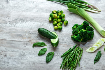 Fresh green food on a light table. Avocados cucumbers cabbage apples beans kiwi onions broccoli. The concept of healthy food, detox vegetarianism. Copy space flat lay.
