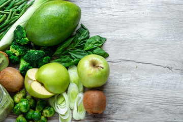 Fresh green food on a light table. Avocados cucumbers cabbage apples beans kiwi onions broccoli. The concept of healthy food, detox vegetarianism. Copy space flat lay.