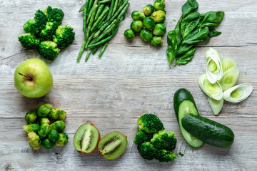 Fresh green food on a light table. Avocados cucumbers cabbage apples beans kiwi onions broccoli. The concept of healthy food, detox vegetarianism. Copy space flat lay.