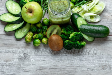 Fresh green food on a light table. Avocados cucumbers cabbage apples beans kiwi onions broccoli. The concept of healthy food, detox vegetarianism. Copy space flat lay.