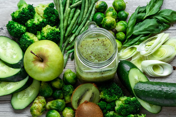 Fresh green food on a light table. Avocados cucumbers cabbage apples beans kiwi onions broccoli. The concept of healthy food, detox vegetarianism. Copy space flat lay.