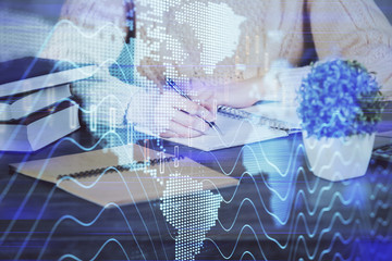 Forex graph on hand taking notes background. Concept of research. Double exposure