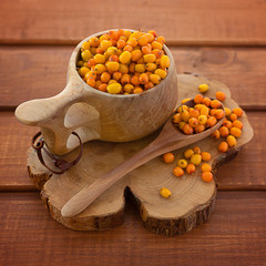 sea buckthorn in a bowl on a wooden square background