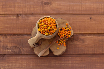 sea buckthorn in a bowl on a wooden background close up