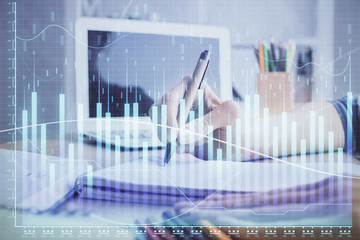 Financial forex charts displayed on woman's hand taking notes background. Concept of research. Double exposure