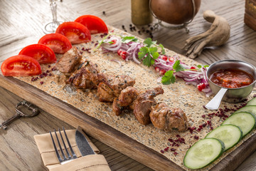 chicken shish kebab on lavash bread with fresh cucumber and tomato on wooden table