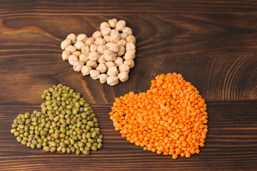  heart shaped Chick-pea, mung bean and orange lentils. wood background 