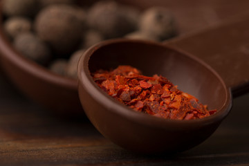 Black pepper peas and red pepper close-up, macro photo. Black pepper peas in a brown  measuring spoons