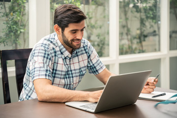 Fototapeta premium Portrait of focused young startup entrepreneur working with laptop in home ,start up concept.