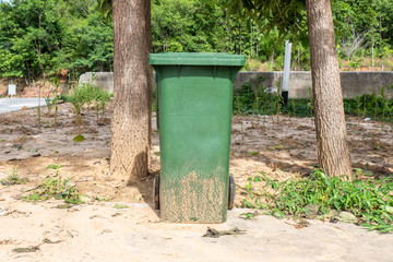 Fototapeta premium Green Plastic Trash with Wheels and Lid in Park