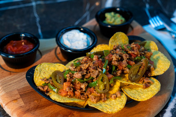 Nacho served with sauces and meat with jalapeños