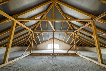Attic of a building with wooden beams of a roof structure and a small window. - obrazy, fototapety, plakaty