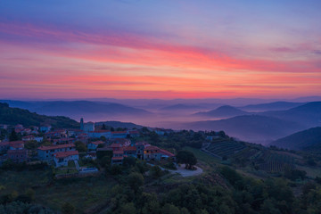 Sunrise in the mountains. The Golden-pink sky, mountains, morning fog and a small village on the mountainside are depicted. Istria, Croatia. The view from the top. Copy space.