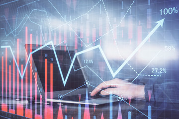 Double exposure of man's hands writing notes with laptop of stock market with forex graph background. Top View. Concept of research and trading.