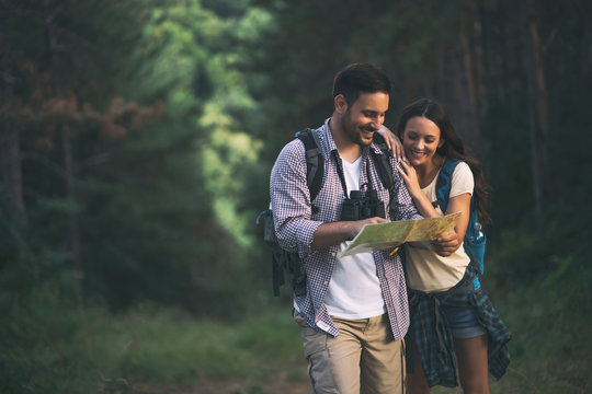 Happy Couple Is Hiking In Forest. They Are Looking At Map.