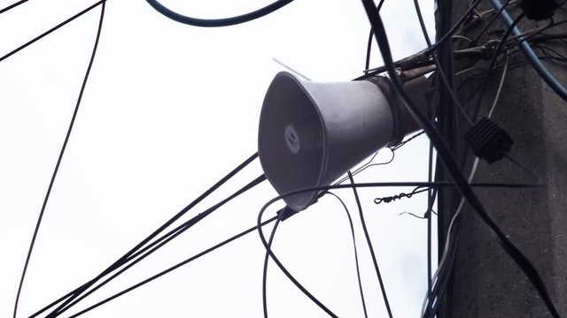 a street speaker hanging on an electric pole with many wires on the street. street speaker on a pillar. 4k. 4k video. 60 fps