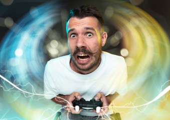 Enthusiastic gamer. Joyful young man holding a video game controller being full of emotions...