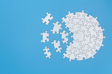 Unfinished white jigsaw puzzle pieces on blue background,  Copy space.