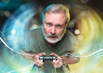 Breathtaking new life. Senior man holding a video game controller isolated on colorful background....