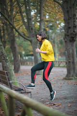 Sporty woman doing toe taps exercise on a city park bench in autumn. Female athlete exercising outdoor.