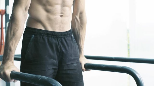 Athletic man working out on dip bars at the gym